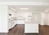 Thumbnail 28 of 42 - A kitchen with white cabinets and a wooden floor.