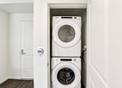 Thumbnail 41 of 42 - A white washing machine and dryer in a small laundry room.