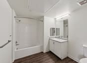 Thumbnail 39 of 42 - A white bathroom with a tub, sink, and mirror.