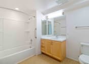 Thumbnail 14 of 17 - A white bathroom with a wooden cabinet and a white toilet.