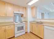 Thumbnail 16 of 17 - A kitchen with wooden cabinets and a white stove top oven.