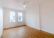 Thumbnail 6 of 17 - A room with wooden floors and two windows.