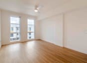 Thumbnail 9 of 17 - A room with wooden floors and two windows.
