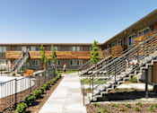 Thumbnail 3 of 11 - A man is walking down a path in front of a building with a pool.