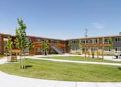 Thumbnail 4 of 11 - A large building with a lot of windows and a green lawn in front.