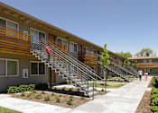 Thumbnail 6 of 11 - A row of modern townhouses with a woman walking in front.