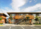 Thumbnail 8 of 11 - A large wooden building with a staircase leading to the entrance.