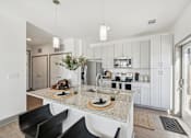 Thumbnail 6 of 26 - A modern kitchen with a granite countertop and black chairs.