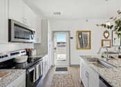 Thumbnail 12 of 26 - A kitchen with granite countertops and stainless steel appliances.