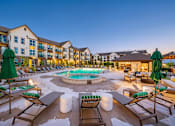 Thumbnail 2 of 26 - A large outdoor pool area with lounge chairs and umbrellas.