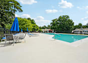 Thumbnail 7 of 107 - A pool with a blue umbrella and chairs.
