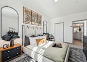 Thumbnail 6 of 10 - A bedroom with a bed, nightstand, and a large mirror.