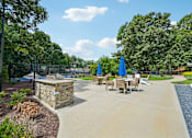 Thumbnail 98 of 107 - A sunny day at the park with a stone structure and tables set up for outdoor dining.