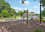 Thumbnail 96 of 107 - A playground with a swing set and a building in the background.