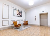Thumbnail 12 of 32 - a lobby with two chairs and a painting on the wall at 26 West, Managed by Buckingham Urban Living, Indianapolis