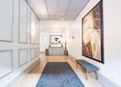 Thumbnail 11 of 32 - a view down a hallway with a bench and a large painting on the wall at 26 West, Managed by Buckingham Urban Living, Indianapolis