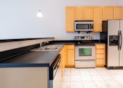 Thumbnail 1 of 32 - a kitchen with black countertops and wooden cabinets at 26 West, Managed by Buckingham Urban Living, Indianapolis