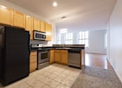 Thumbnail 5 of 32 - a kitchen with wooden cabinets and black appliances at 26 West, Managed by Buckingham Urban Living, Indianapolis