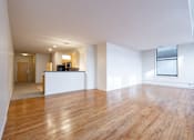 Thumbnail 21 of 32 - an empty living room with hardwood floors and a kitchen in the background at 26 West, Managed by Buckingham Urban Living, Indianapolis