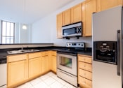 Thumbnail 2 of 32 - a kitchen with wooden cabinets and stainless steel appliances at 26 West, Managed by Buckingham Urban Living, Indianapolis