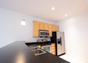 Thumbnail 3 of 32 - a kitchen with a black counter top and stainless steel appliances at 26 West, Managed by Buckingham Urban Living, Indianapolis