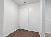 Thumbnail 85 of 107 - A white door with a gold handle is in a room with white walls and a wooden floor.
