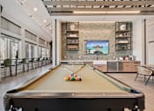 Thumbnail 16 of 26 - A pool table is in the middle of a room with a brick wall and a picture of a beach house.