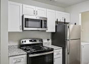 Thumbnail 77 of 107 - A kitchen with a black refrigerator, black stove, and white cabinets.