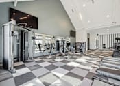 Thumbnail 22 of 26 - A gym with a variety of equipment including a squat rack, bench press, and a rowing machine.