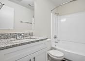 Thumbnail 82 of 107 - A white bathroom with a granite countertop and a white bathtub.