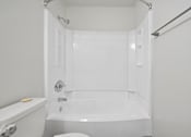 Thumbnail 83 of 107 - A white bathroom with a tub, toilet and sink.