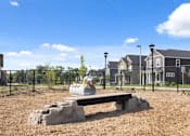 Thumbnail 24 of 28 - Fenced dog park with agility tunnel and bench seating at Nook Nine apartment community