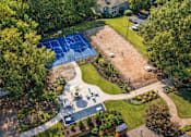 Thumbnail 3 of 49 - A tennis court is surrounded by trees and a grassy area.