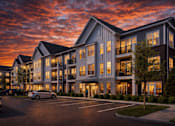 Thumbnail 1 of 10 - A large, modern building with a parking lot in front of it.