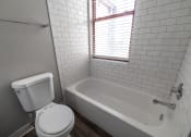 Thumbnail 26 of 35 - Bathroom with window and updated tiled bathtub at The Argyle on Mass Ave, Indiana, 46202