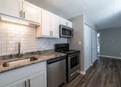 Thumbnail 22 of 35 - Open kitchen layout with white cabinets, white subway tile backsplash, and granite countertops at The Argyle on Mass Ave, Indianapolis, IN
