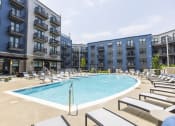 Thumbnail 6 of 53 - a large swimming pool with chaise lounge chairs and a building in the background