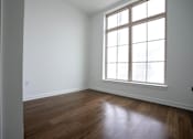 Thumbnail 9 of 22 - A room with a large window and wooden floors.