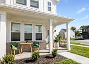 Thumbnail 17 of 37 - A white house with a porch and green chairs.