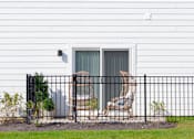 Thumbnail 23 of 37 - A white house with a black fence and two chairs outside.