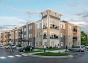 Thumbnail 7 of 8 - A modern apartment complex with cars parked in front.