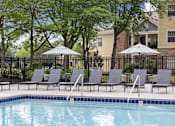 Thumbnail 28 of 34 - Shaded poolside seating area with loungers and umbrellas at Center Point Apartments offering a peaceful spot to relax outdoors.