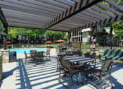Thumbnail 3 of 10 - a patio with tables and chairs next to a swimming pool at Elea Apartments in Marietta, GA