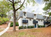 Thumbnail 1 of 10 - a white house with trees and a sidewalk at Elea Apartments in Marietta, GA