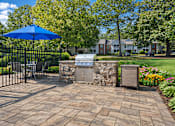 Thumbnail 106 of 107 - A blue umbrella is on a patio with a stone wall and a mailbox.