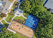 Thumbnail 102 of 107 - A tennis court surrounded by trees and a playground.