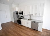 Thumbnail 4 of 22 - A kitchen with white cabinets and a wooden floor.