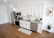 Thumbnail 3 of 22 - A kitchen with white cabinets and a wooden floor.