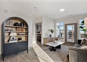 Thumbnail 10 of 27 - Model apartment living room at Montage West Lafayette featuring an open layout, modern furnishings, decorative shelving, and large windows with natural light.
