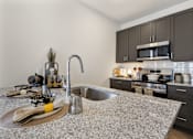 Thumbnail 3 of 27 - Modern apartment kitchen at Montage West Lafayette with granite countertops, stainless steel appliances, and large center island.